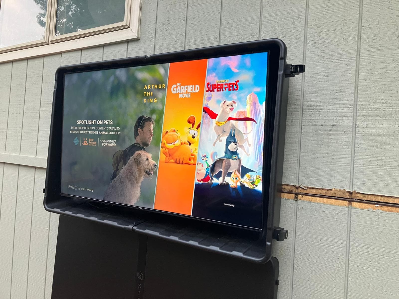 Weatherproof TV enclosure mounted outdoors, streaming content